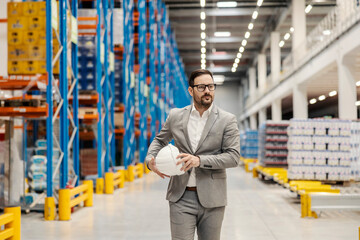 A businessman walking trough the big distribution center and checking on goods.
