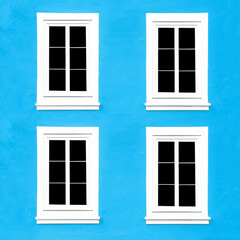 Fototapeta na wymiar PVC Windows. Architecture background. Vibrant color blue wall facade. Small town house exterior. Street of European city building. Four window frames isolated on empty wall. Simple windows in a row.