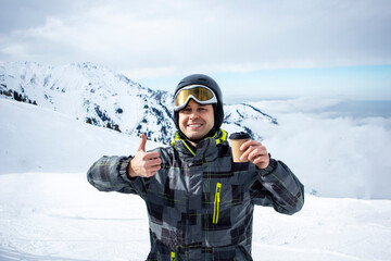 a snack at the ski resort. the guy drinks on the ski slope. mockup of a coffee cup