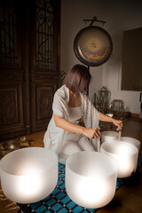 Woman in A serene sound healing therapy session with a practitioner playing crystal singing bowls...