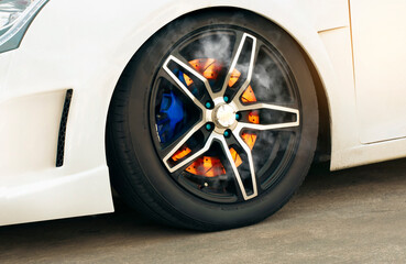 Close up shot of a burning disc brake in a wheel of a sports car.