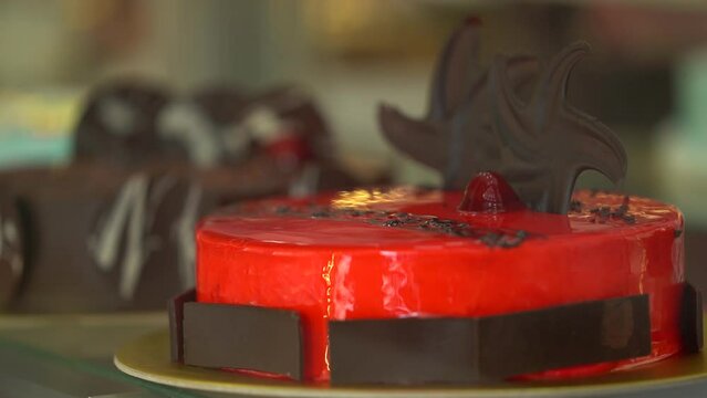 Red cake. A circle of strawberry cake is decorated with chocolate and sold in a display case