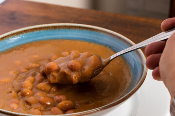 Hand holding spoon full of traditional Colombian soup beans