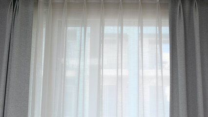 Voile curtain in front of window with grey curtains to either side