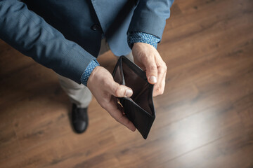 Well dressed man holding empty leather wallet. Financial crisis and bankruptcy concept