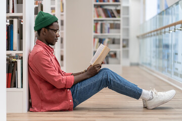 Focused Black student man book lover spending free leisure time in library, African American guy...