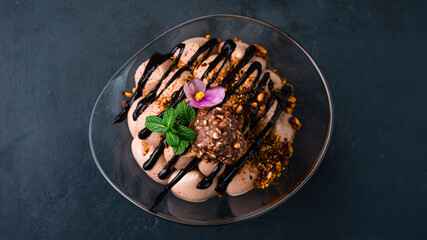 Tiramisu dessert with chocolate candy, nuts, mint and sweet sauce.