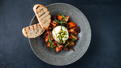 Burrata cheese with anchovies, tomatoes, microgreens, fried bread slices and sauce.