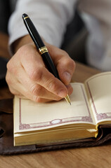 A businessman sits at a table and makes notes in a notebook.