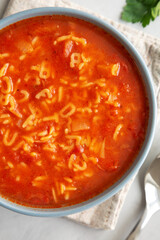 Homemade Alphabet Soup in Tomato Sauce in a Bowl, top view. Overhead, from above, flat lay. Close-up.