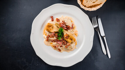 Italian food pasta with bacon pieces and sauce in plate.