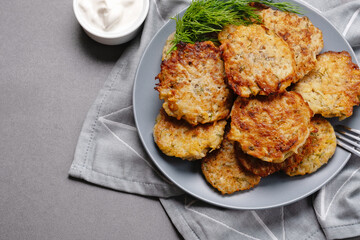 Close up view of potato pancakes. Potatoes pancakes latkes, flapjacks, hashbrown or potato vada on gray plate over gray wooden table, with fresh dill and sour cream. Copy space for text