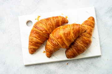 Fresh Croissants on cutting board at white table. Fresh bakery. Top view image.
