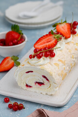 Meringue roll cake with cream and berry confiture decorated with fresh strawberries and red currants.  Delicious dessert. Selective focus, close up