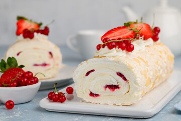 Meringue roll cake with cream and berry confiture decorated with fresh strawberries and red currants. Summer dessert. Selective focus
