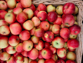 ripe fresh yellow-red apples in a wicker basket on the market counter