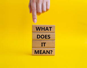 What does it mean symbol. Wooden blocks with words What does it mean. Beautiful yellow background. Businessman hand. Business and What does it mean concept. Copy space.