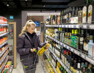 Young woman shopping in supermarket, reading product information.