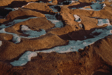 sandy texture in the "golden hour" tone with depressions filled with snow