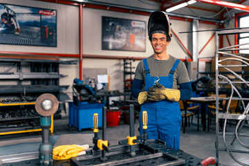 A man working in a workshop is smiling in front of his workbench, working on spacing and fixing...