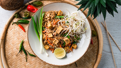 Udon noodles stir fry with chicken, carrots, onions, lime, green sprouts and nuts.