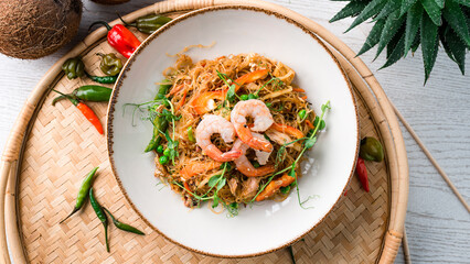 Glass noodles stir fry with shrimp, chicken, carrots, onions, sweet peppers, green peas and microgreens.