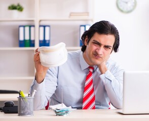 Young male employee suffering in the office