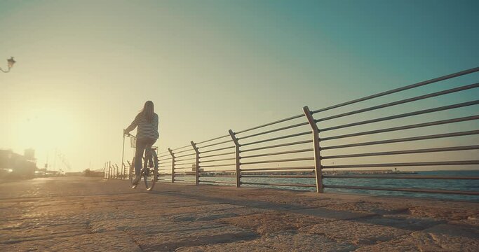 Carefree woman with bike riding on beach having fun, on the seaside promenade on a summer day. Summer Vacation. Travel and lifestyle Concept.	