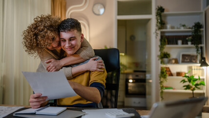 Young man male student teenager and his mother celebrate scholarship read mail letter happy exited...