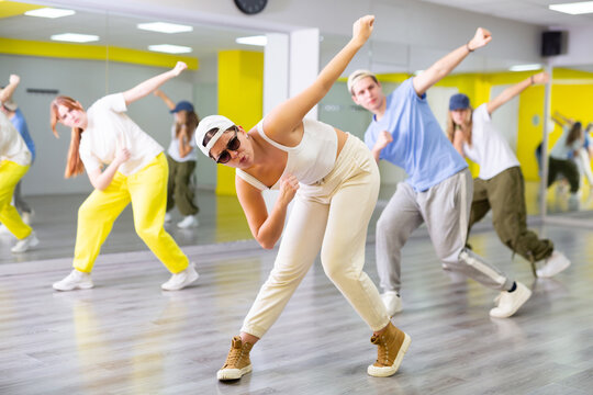 Dynamic young girl in sunglasses training breakdance Toprock moves during workout session. Teens doing breakdance in dance hall