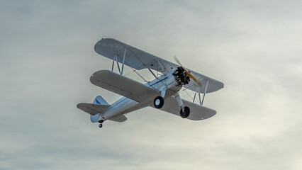 World War II vintage 1943 PT17 Stearman biplane flies overhead at dusk