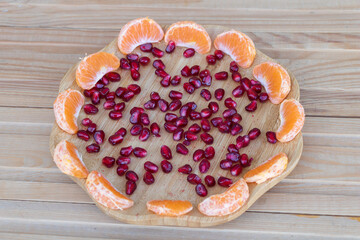 A Colorful Arrangement of Tangerines and Pomegranate on a Wooden Plate