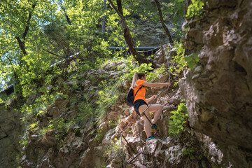 Female hiker climbing metal ladder on a ridge, enjoying active vacation and beautiful outdoor trail
