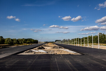 Budowa nowej autostrady. Montaż barier ochronnych i znaków przy nowo budowanej autostradzie. Nowy asfalt. - obrazy, fototapety, plakaty