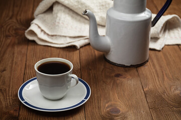 cup of coffee and vintage coffeepot on wooden table.