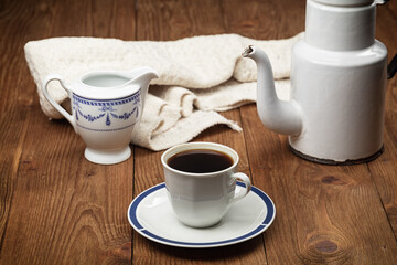 cup of coffee and vintage coffeepot on wooden table.