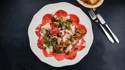 Appetizer of beef carpaccio withCold appetizer of beef carpaccio with mushrooms, parmesan and microgreens.