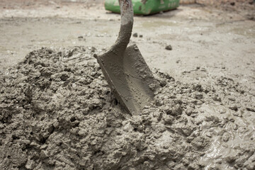 Horizontal image of concrete mixing shovel in the middle of the mix. Preparing concrete