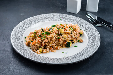 Uzbek pilaf with meat, carrots, zucchini, tomatoes, onions and herbs.