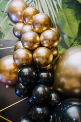 Background, texture of many beautiful round black, golden, colored, balloons on the indoor photo zone in the interior. Close-up photography, holiday, birthday, wedding.