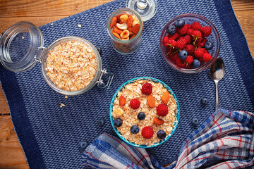 Oatmeal porridge in ceramic bowl decorated with fresh berries served with honey. Healthy breakfast concept.