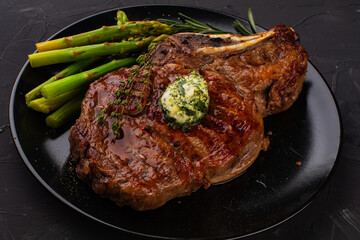 Juicy medium rare beef steak on ceramic board with herbs spices and salt.