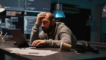 Software engineer yawning and falling asleep on desk, being exhausted and trying to work on new...