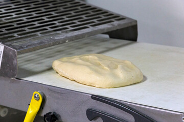 Pastry dough on the table of press machine. Automation of dough production in the bakery