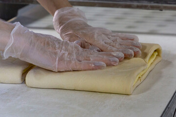 Baker in gloves working with raw dough. Process of making homemade pastry