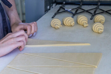 Woman rolls the dough into a croissant on the table one by one. Homemade pastry croissants baking