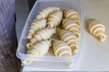 Half-done uncooked croissants into a container