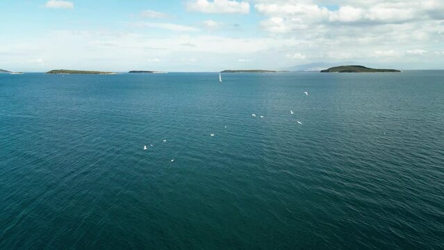 Aerial of sun yacht sail in agean sea. White boat at open sea. Summer cruise on sailboat at sunlight with clouds. urla izmir sea coast with water transport. . High quality 4k footage