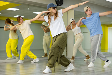 Teenager girl in cap dances modern dances in dance studio