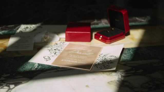 Wedding rings and decorated invitation illuminated by sun